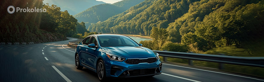 Эко-шины на легковом автомобиле — KIA на извилистой трассе среди зелёного леса